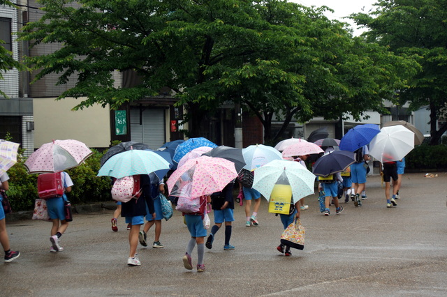 雨の日にランドセルで登校する子どもたち